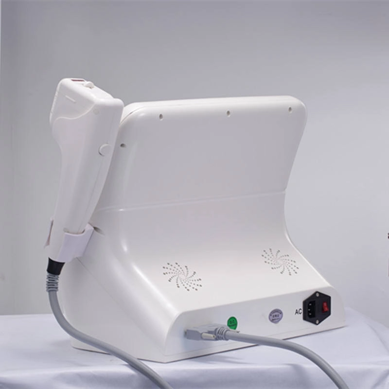 Rear view of a white cosmetic laser machine with applicator and cords. - HUIMAIN